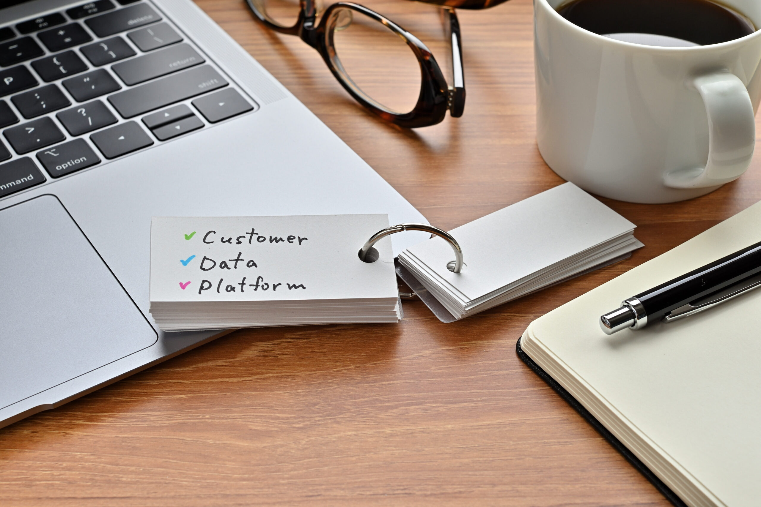 There is a piece of paper with a graph printed on it, a clipboard, and an open vocabulary book on the desk. There is the word Customer Data Platform on it.